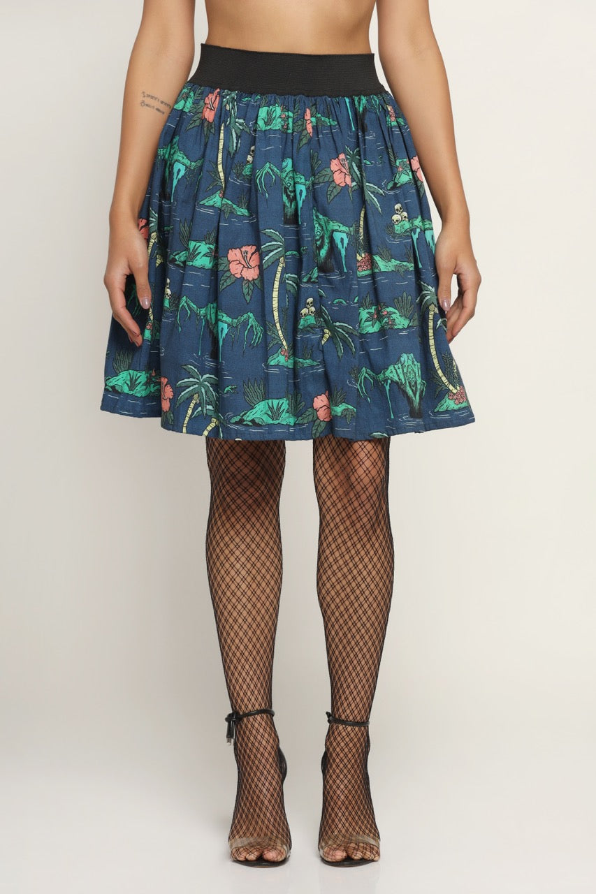 A navy-colored skirt with a floral pattern, featuring a mix of green and red flowers, displayed on a mannequin that also shows a pair of black fishnet stockings and a pair of high-heeled sandals.