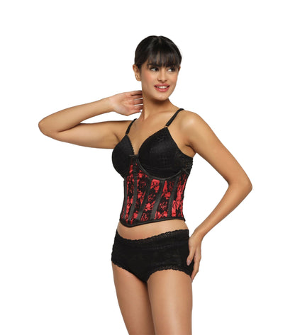 A woman modeling a black lace lingerie set with a red and black patterned corset top and matching black lace briefs, photographed against a plain white background.