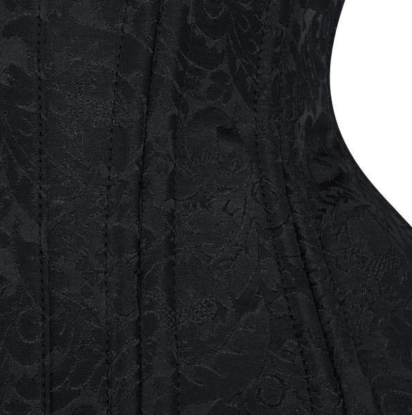Close-up of a black jacquard fabric with a subtle floral damask pattern, showing vertical pleats and a white curved background shape on the right side.