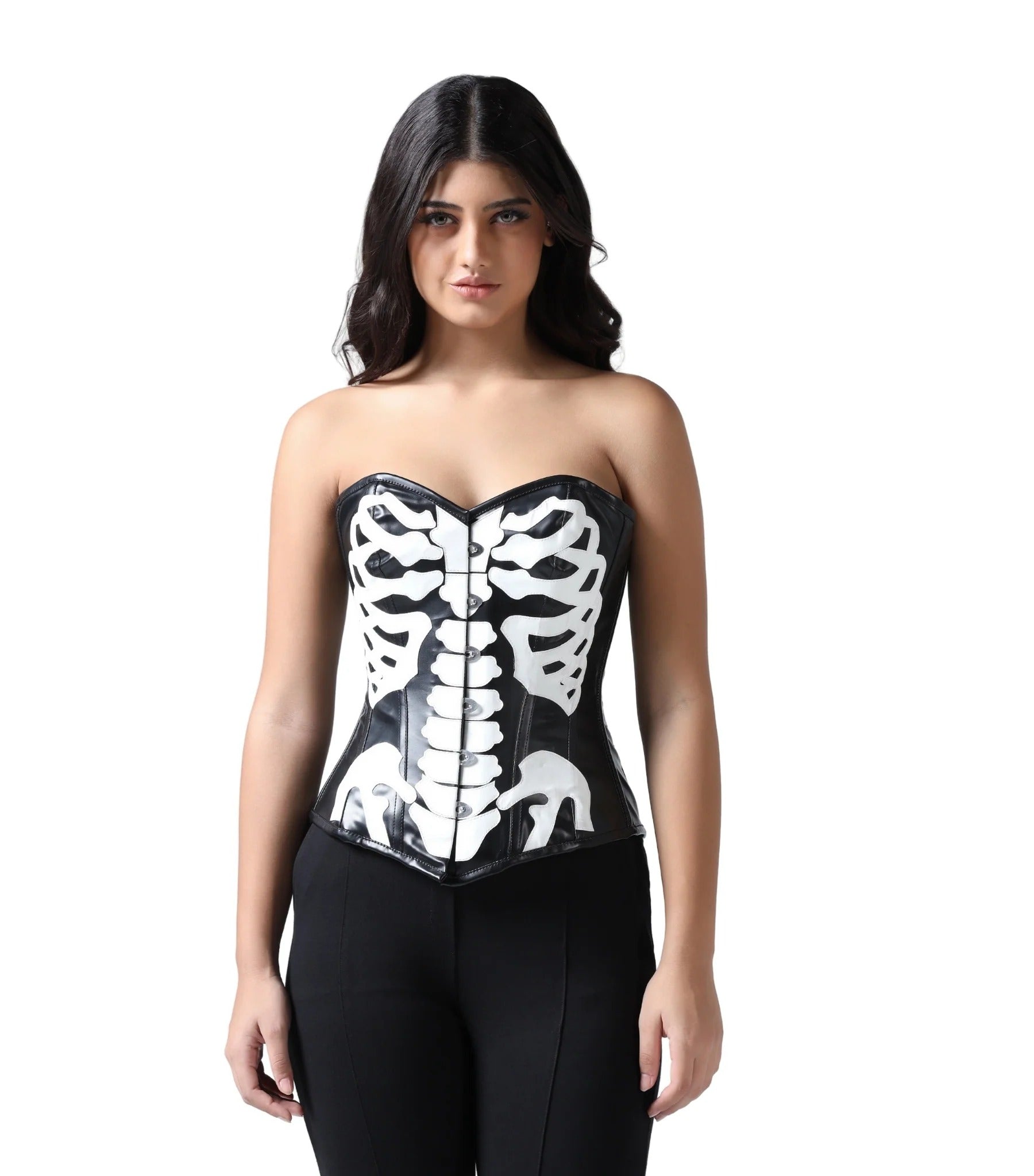 A woman modeling a glossy black latex strapless corset with a white skeleton ribcage print, paired with black pants, against a solid white background.