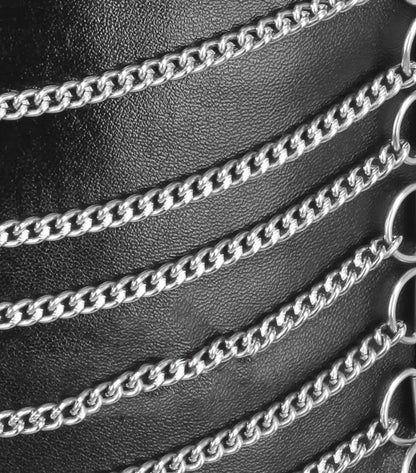 Close-up of a black textured leather or faux-leather surface decorated with multiple horizontal silver metal chains and circular ring details.